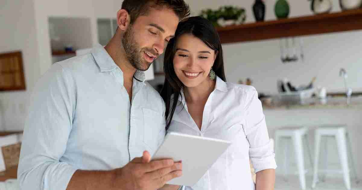 Loving couple at home looking at social media on a digital tablet