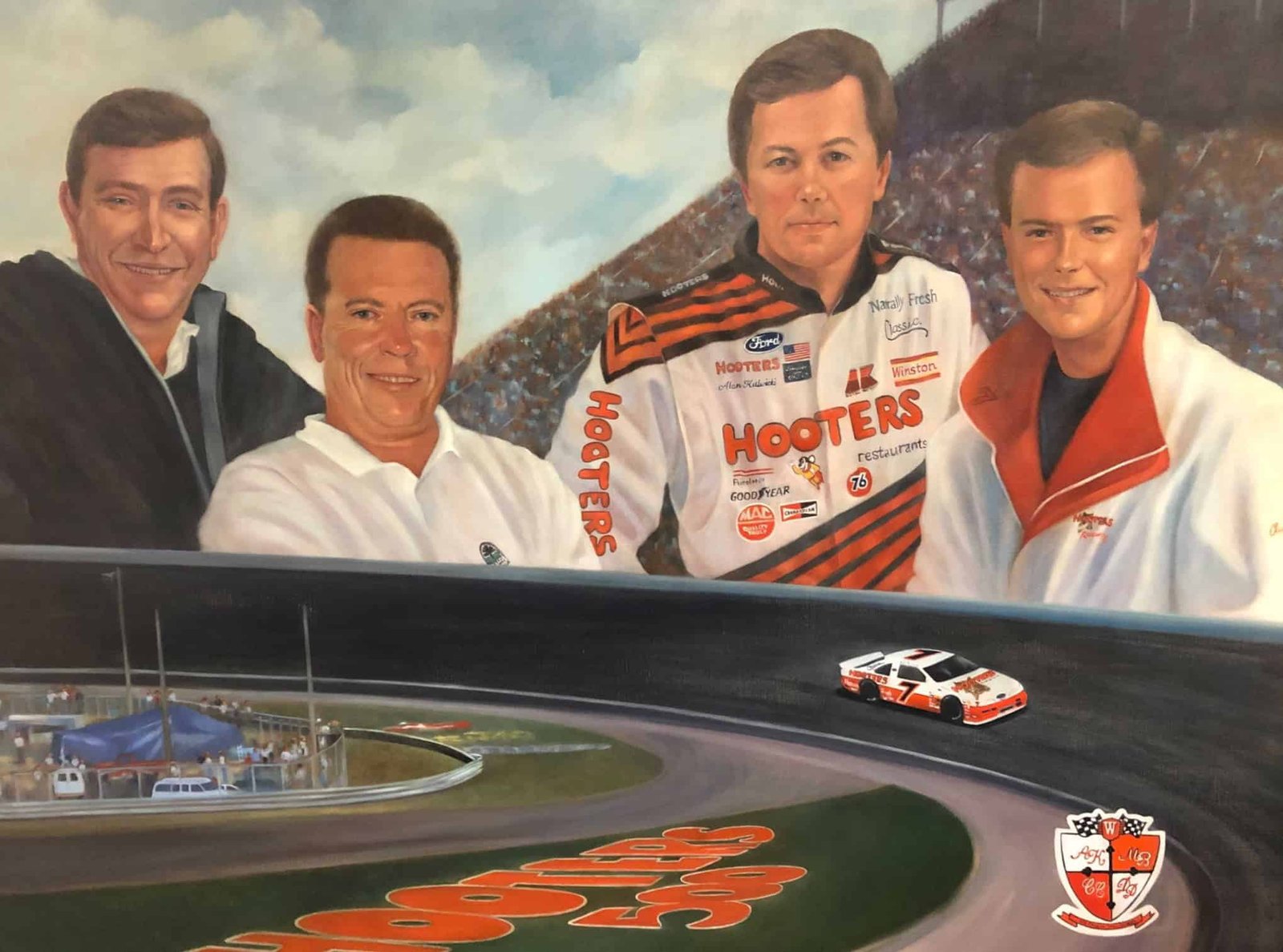 Vintage racing team photo featuring NASCAR driver Steve D. deGuzman in a Hooters-sponsored racing suit, surrounded by team members with a race car on a track backdrop, highlighting motorsports success and racing history.